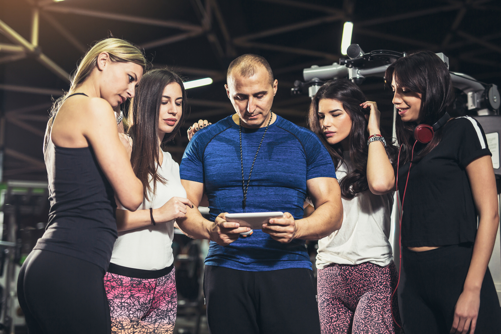 gym people in sports equipment looking at a tablet